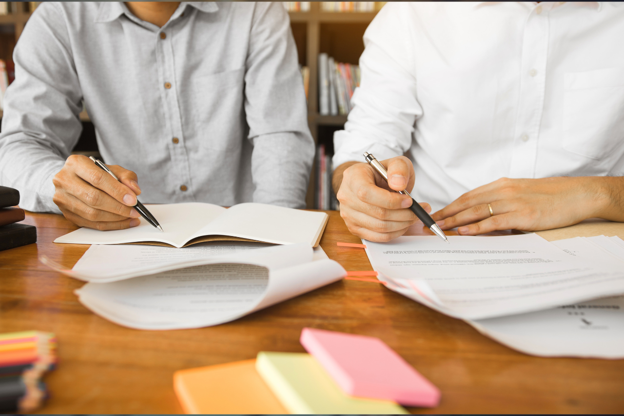 How to find good private GCSE tuition – two males sat at a table, pens poised over papers. Cropped so you only see their arms and torsos.